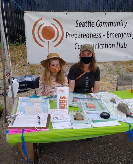 A young girl and her mother sit at a Hub information table